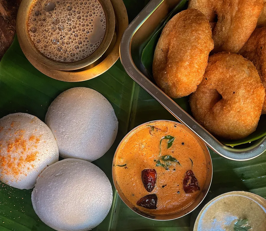 Idli, vada, sambar, chutney and filter coffee served on a banana leaf
